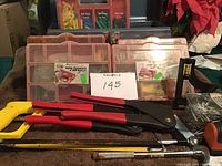 Photo showing 2 riveting tools, 2 red plastic organizer boxes with assorted fasteners and rivets, yellow hacksaw, and other hand tools.