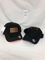 Two new black Chevrolet branded ballcaps side by side on a white background with tags attached