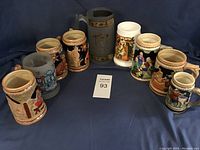 Eight assorted beer steins arranged in a semi-circle showing various colors, sizes, and designs including medieval and traditional European scenes.