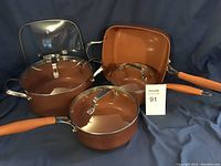 Full set of eight copper-colored cookware items displayed including small to large pots with lids, square grill pan, and multiple glass lids.
