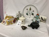 Full view of assorted bric a brac including bunny dish, turtle figurine, Blue Stilton cheese container, decorative plate, human figure ceramics, and bird tiles