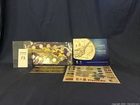 Four coin sets displayed on a draped background including a map shaped coin collection, Winter Olympics coin display, and a provincial flags themed coin holder.
