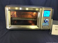Front view of the Cuisinart steam convection oven showing the stainless steel body, clear window, digital display lit to 350°F, control knob, and buttons for light and start/cancel.
