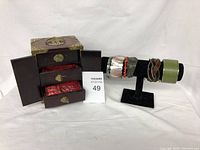 Photo showing wooden jewelry case with brass hardware and multiple compartments plus black bracelet stand loaded with bracelets.