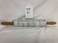 Front view of marble rolling pin showing polished marble cylinder with attached wooden handles.