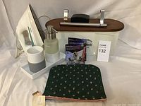 Full lot overview showing iron, Norwex bathroom set, pouch, batteries, and small boxed items on a white backdrop.