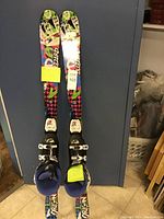 Photo of Blizzard skis showing colorful design with bindings and attached notes indicating size and brand.