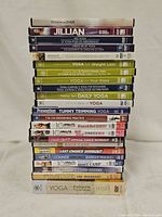 Photo showing the stacked DVD cases with titles visible, depicting a diverse collection of workout programs primarily focused on yoga and other fitness routines.