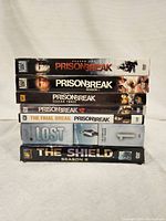 Stack of seven TV season DVD box sets including Prison Break seasons 1-4 and The Final Break, Lost season 1, and The Shield season 2.