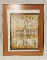 Framed abstract brown toned artwork with tree trunks in a light brown matte and thin metallic gold frame.