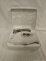 GE hand mixer and attachments set in white plastic case open on a neutral background.