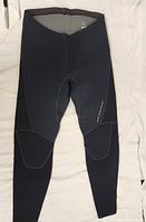 Front view of dark grey/black neoprene pants showing padded knee sections and smooth fabric texture.