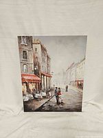 Front view of Paris cafe canvas painting showing street scene with buildings, cafe with red awnings, and people.