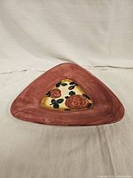 Front view of the triangular plate showing the pink outer border and floral design in the center.