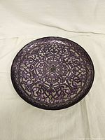 Front side of the decorative metal plate showing purple intricate design on silver background