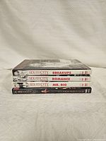 Four Sex and the City DVD cases stacked horizontally, showing titles on the spine: Breakups, Romance, Mr. Big, and Sex and the City.