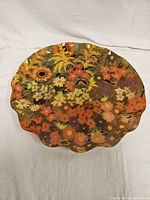 Top view of vintage floral tray showing detailed multi-colored flower pattern with orange, yellow, brown, cream flowers and scalloped edges.