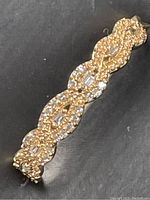 Close-up of ring top showing twisted rope/infinity pattern set with round and baguette diamonds on a dark background