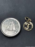 Pendant shown next to a 2016 Canadian 10-cent coin for size reference, highlighting small and delicate size.