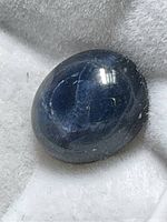 Close-up image of the oval cabochon enhanced star sapphire showing the blue color and star effect.