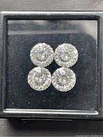 Four round laser cut moissanite gemstones shown in black display box, photographed from above to capture brilliance, size, and cut details.