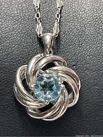 Close-up view of the sterling silver pendant with central round aquamarine gemstone showing the swirl design in detail.
