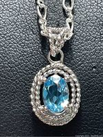 Close-up of the blue topaz pendant on sterling silver chain, showing stone and twisted rope design of pendant.