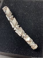 Photo showing close-up view of sterling silver bracelet's linked design on a black background.