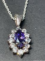 Close-up front view of sterling silver necklace pendant with marquise purple cubic zirconia surrounded by clear cubic zirconia stones.