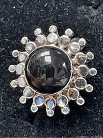 Close-up photo of sterling silver ring with a black onyx cabochon surrounded by silver bead accents.