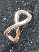 Front angle view of sterling silver infinity loop ring on a black background.