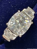 Close-up image of the ring showing the cushion-cut cubic zirconia center stone with baguette and trapezoid side stones in a sterling silver band.