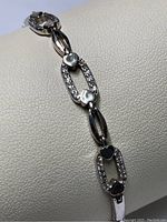 Close-up photo of sterling silver bracelet showing rectangular CZ-studded links and heart accents