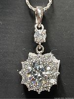 Close-up photo of sterling silver cubic zirconia necklace pendant showing large center stone and halo of smaller stones.