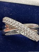 Close-up image of the sterling silver ring showing the crossing bands, one plain and one encrusted with cubic zirconia stones.