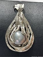 Front view of pendant showing organic silver teardrop design with pearl center on black background.