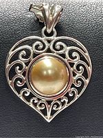 Close-up front view of the sterling silver heart-shaped pendant with fresh water pearl center on a black background.