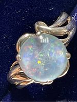 Close up view of sterling silver ring with round opalite stone showing blue and orange iridescence in natural light.