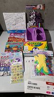 Photo showing unicorn coloring canvas, Word Search puzzles, Halloween coloring books, purple organizer, and Crayola crayons.