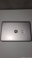 Closed view of the silver HP laptop lid with HP logo and auction sticker.