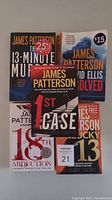Photo showing 5 James Patterson paperback books stacked: The 13-Minute Murder, Stolen, 18th Abduction, Lucky 13, 1st Case. Various price stickers on covers, used condition.