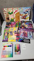 Lot contents displayed on surface including multiple kids activity and colouring books with popular characters, watercolor paints, crayons, and washable markers.
