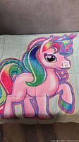 Close view of the My Little Pony design on the kids weighted blanket, showing colorful pony with rainbow hair and unicorn horn on light green background.