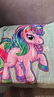 Front view of the My Little Pony weighted blanket showing colorful pony design on light blue fabric.