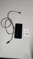 Black Samsung Galaxy S9 smartphone and charger cable on flat surface from top view