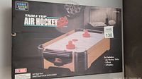 Boxed tabletop air hockey game set with image and branding on packaging.