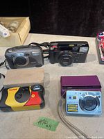Four cameras on a table: Kodak DC280 700m, Pentax, Kodak disposable, Sony Cybershot digital 8.1 MP