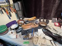 Overview photo showing various belts of different colors and materials including leather and fabric, some rolled and others laid flat with visible buckles and clasps.
