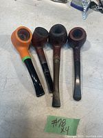 Four mostly vintage pipes in a row on a flat surface showing variety and condition.