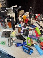 Overview of assorted lighters on a surface, showing variety in style and design including torch and plastic refillables.